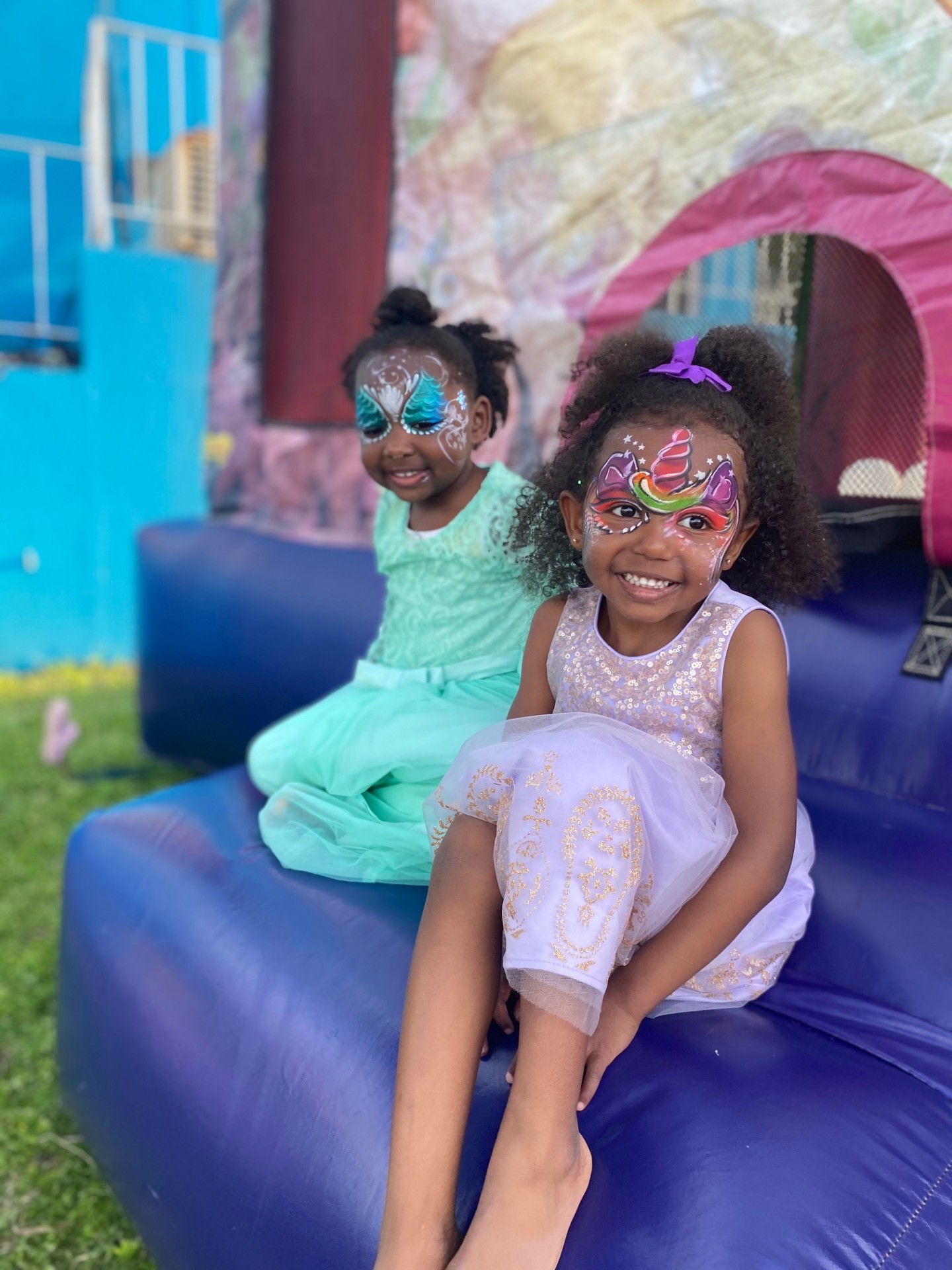 Two girls with unicorn face paint smiling on a bounce castle at a Bermuda party